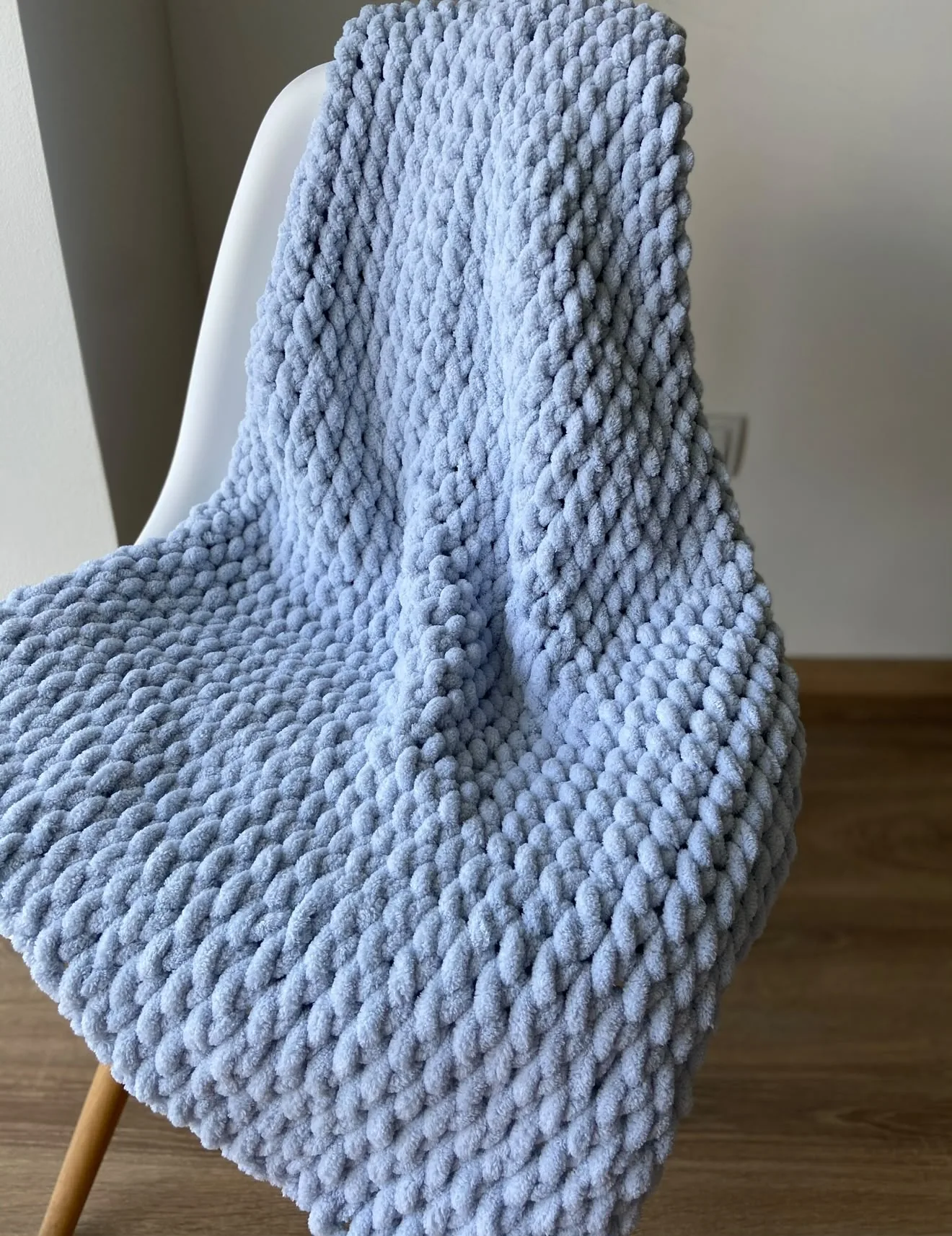Pale blue classic knitted blanket draped over a chair